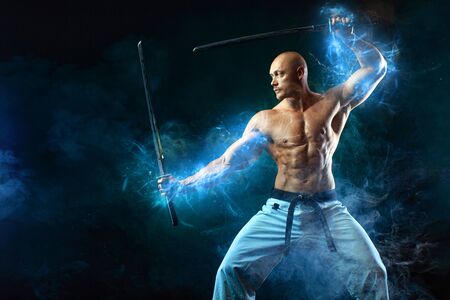 Karate fighter on black background with smoke. Shirtless man samurai with Japanese sword. Fit man sportsmen bodybuilder physique and athlete. Mens sport motivation.の写真素材
