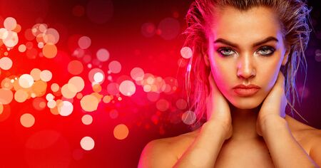 Fashion portrait. Young blonde woman posing on background with red bokeh lights.の写真素材