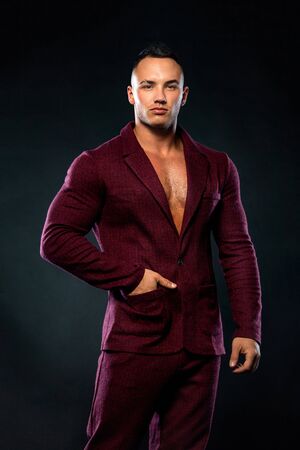 Portrait of handsome stylish man bodybuilder with naked torso in elegant suitの写真素材