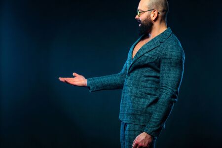 Portrait of bearded man with pointing finger at copyspace isolated over dark blue background. Guy in sunglasses pick on great idea.の写真素材