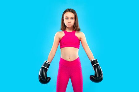 Boxing and fitness concept. Sportsman, girl kid boxer fighting in gloves on blue background.の写真素材