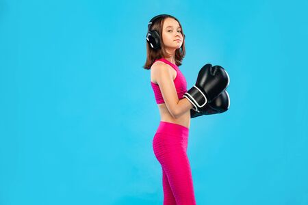Boxing and fitness concept. Sportsman, girl kid boxer fighting in gloves on blue background.の写真素材