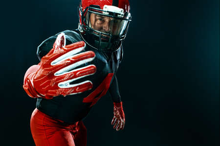 American football player, athlete sportsman in red helmet on black background. Sport and motivation...