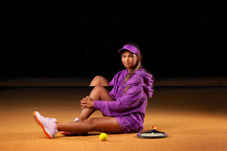 Portrait of kid - tennis player. Beautiful girl athlete with racket in pink sporswear and hat on...