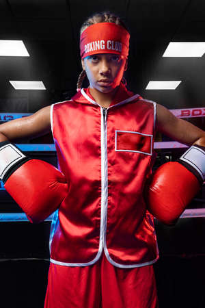Kids sport concept. Girl sportsman muay thai boxer fighting in gloves in boxing gym.の写真素材