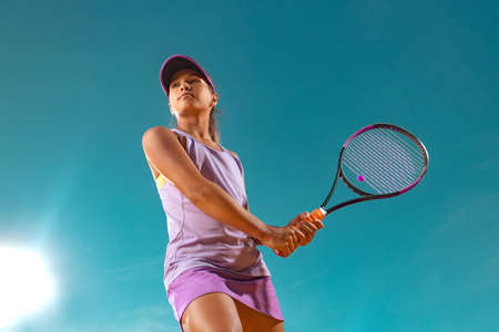 Teenager tennis player. Beautiful girl athlete with racket in pink sporswear and hat on tennis court. Fashion and sport concept.の写真素材