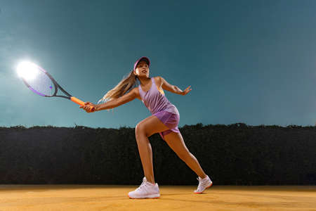 Tennis player. Beautiful girl teenager and athlete with racket in pink sporswear and hat on tennis court. Fashion and sport concept.の写真素材