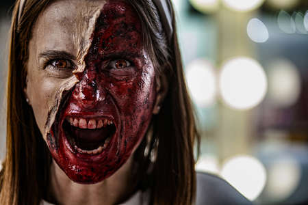 Zombie makeup on Halloween 2020. Creative art make-up for eve of All Saints Day party. Creepy bloody face. Close-up portrait of horrible woman. Horror.の写真素材