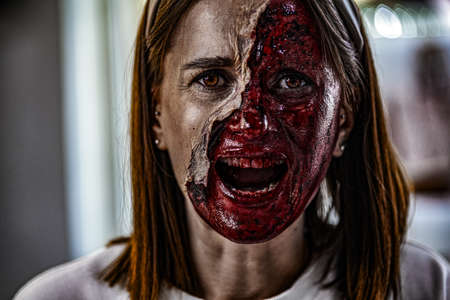 Zombie makeup on Halloween 2020. Creative art make-up for eve of All Saints Day party. Creepy bloody face. Close-up portrait of horrible woman. Horror.の写真素材