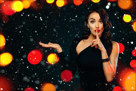 Black friday sale concept with beautiful girl with curly hair for shop on blackfriday. Happy young woman standing isolated over dark background pointing to looking left.の写真素材