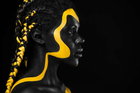 Yellow and black body paint. Woman with face art. Young girl with colorful bodypaint. An amazing...