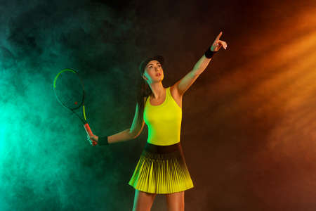 Tennis player with racket in sportswear. Woman athlete playing dark background.の写真素材