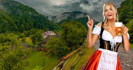 Oktoberfest girl waitress with beer. Woman wearing a traditional Bavarian or german dirndl on octoberfest, serving big mugs with drink on mountains background. Woman pointing to looking up.の写真素材