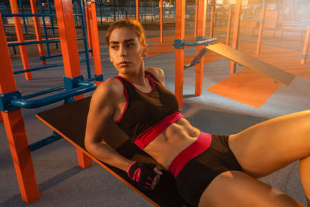 A young girl doing abdominal crunches on the outdoor sports ground