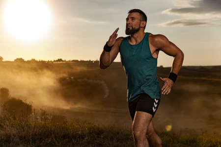 Athlete sprinter run. Strong athletic man running on sunset background wearing in the sportswear. Fitness and sport motivation. Runner concept.の写真素材