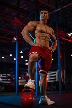 Bodybuilder athlete man pumping up muscles in the gym. Brutal strong muscular guy on fitness workout. Bodybuilding concept.の写真素材