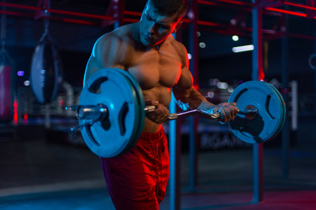 Bodybuilder athlete man pumping up muscles in the gym. Brutal strong muscular guy on fitness workout. Bodybuilding concept.の写真素材