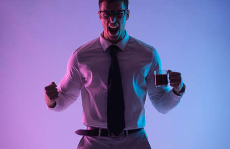 Businessman screams from a charge of cheerfulness after a cup of coffee. Man with tea in office.の写真素材
