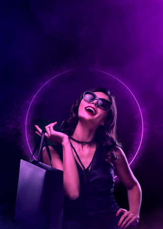 Black friday sale concept. Shopping woman holding grey bag isolated on neon background in holidayの写真素材