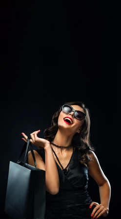 Black friday sale concept. Shopping woman holding grey bag isolated on dark background in holidayの写真素材