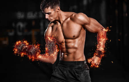 Bodybuilding concept. Brutal strong muscular bodybuilder athletic man pumping up muscles with barbell on black background.の写真素材