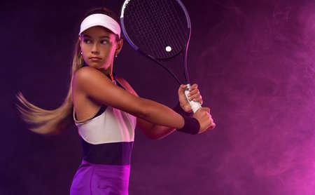 Tennis player. Beautiful girl teenager and athlete with racket in pink sporswear and hat on tennis court. Fashion and sport concept.の写真素材