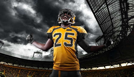 American football player, athlete in helmet with ball on stadium. Sport wallpaper with copyspace.の写真素材