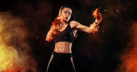Woman boxer on black background in the fire. Boxing and fitness concept.の写真素材