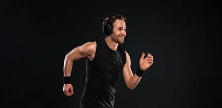 Runner concept. Sprinter run. Strong athletic man running on black background wearing in the sportswear. Fitness and sport motivation.の写真素材