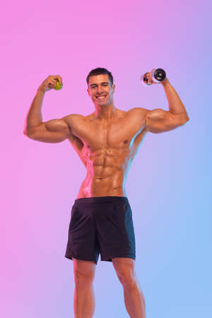 Happy man athlete with dumbbell isolated on pink background. Gym full body workout. Muscular man athlete in fitness gym have havy workout. Sports trainer on trainging. Fitness motivation.の写真素材