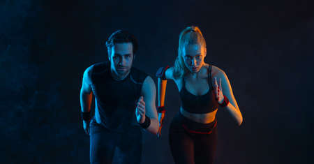 Sprinter run. Strong athletic woman and man running on black background wearing in the sportswear. Fitness and sport motivation. Runner concept.の写真素材