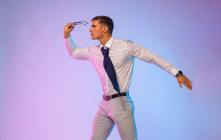 athlete bodybuilder in a white shirt looks through glasses on a purple background. Bsuiness and fitness concept.の写真素材