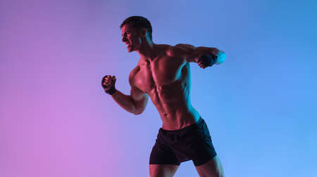 Boxing concept. Sportsman muay thai boxer fighting in gloves. Isolated on neon background. Copy Space.の写真素材
