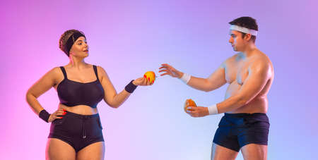 A fat man with a burger, and a vegan woman with apple. Meat versus vegetables. Idea for a social media post on the topic of dietetics.の写真素材