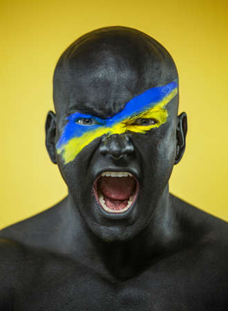 Flag of Ukraine painted on a face of soldier. War between Ukraine and Russiaの写真素材
