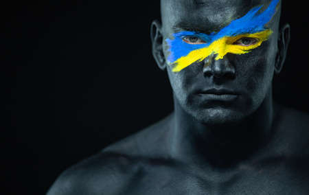 Flag of Ukraine painted on a face of soldier. War between Ukraine and Russiaの写真素材