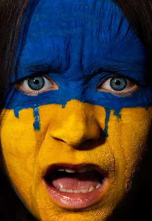 Flag of Ukraine painted on a face on the face of a teenage child. War between Ukraine and Russia. Crying girl with a face art.の写真素材