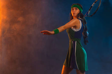 Tennis player with racket in sportswear. Woman athlete playing dark background.の写真素材