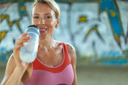 Woman in fitness wear doing workout with a heavy medicine ball outdoors.. Sporty girl with fit body...