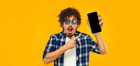 Idea for Mobile App Advertisement. Man Showing Smartphone Screen On Yellow Studio Background....