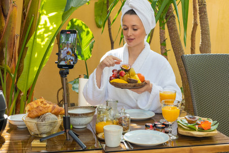 A blogger girl makes a video review of breakfast at a hotel in the Maldives. An influencer creates content for social media. Live online broadcast, photography for womens magazines.の写真素材