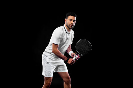 Padel tennis player. Man athlete with paddle tenis racket on black background.の写真素材