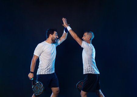 Padel tennis doubles. Two athletes players with racket. Man athlete with paddle racket on court with neon colors. Sport concept. Download a high quality photo for the design of a sports appの写真素材