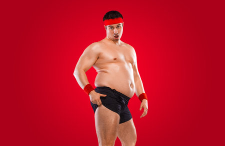 A funny fat man isolated on red background. Obesity and eating disorder. Concept for dietetics and fitness advertising in social networks.の写真素材