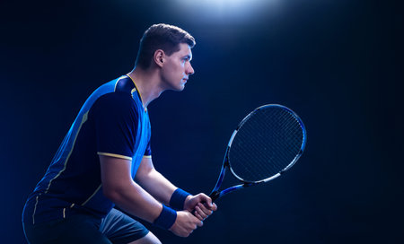 Tennis player with racket closeup. Man athlete playing isolated on black background.の写真素材