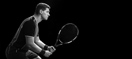 Tennis player with racket closeup. Man athlete playing isolated on black background. Banner for advertisementの写真素材