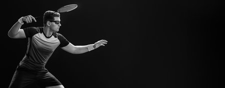 Badminton player. Man with racket and shuttlecock on black background. Individual sports. Sports recreation. Banner for advertisementの写真素材