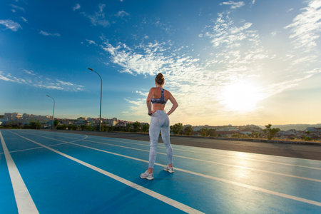 Sporty woman with slim tanned body in sportswear posing on sky background.の写真素材