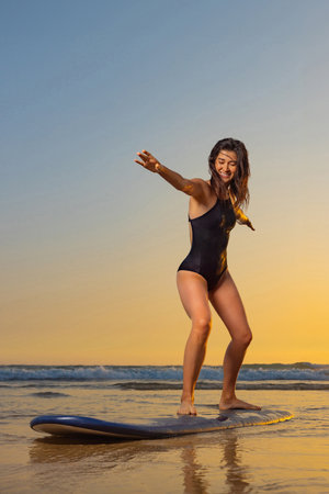 Girl with surf board ready to surfing. Woman surfer holding surfboard on a beach at sunset or sunrise. Surfing at Atlantic ocean.の写真素材