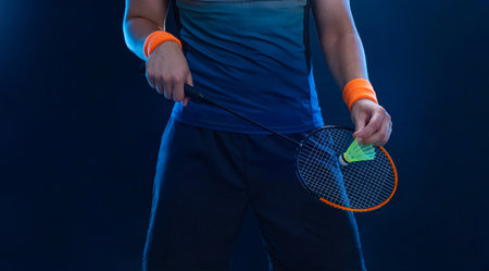 Badminton player close-up photo. Man with racket and shuttlecock on blue background. Individual sports. Sports recreation.の写真素材
